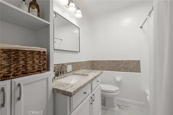 a bathroom with a granite countertop sink a toilet and a mirror