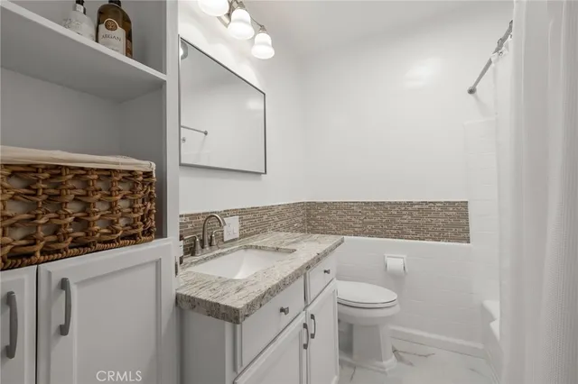 a bathroom with a granite countertop sink a toilet and a mirror