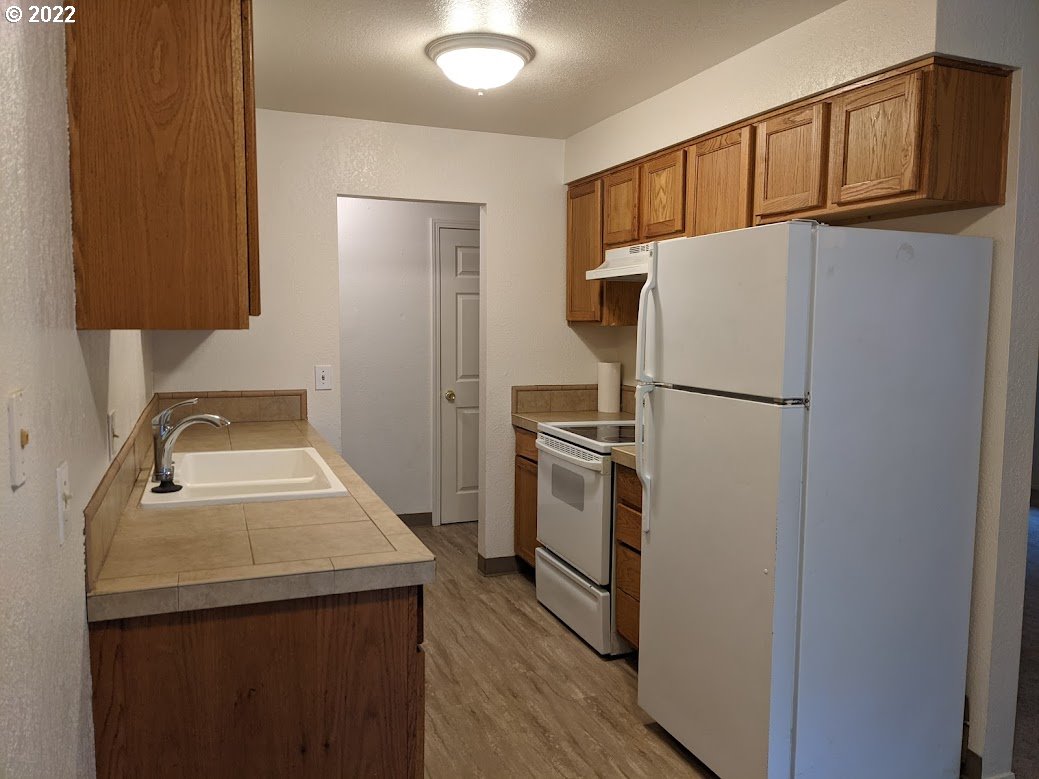 17170 Southwest Merlo Road Beaverton, OR 97003 - Photo 5 of 16 a kitchen with a refrigerator a stove and a sink with wooden floor