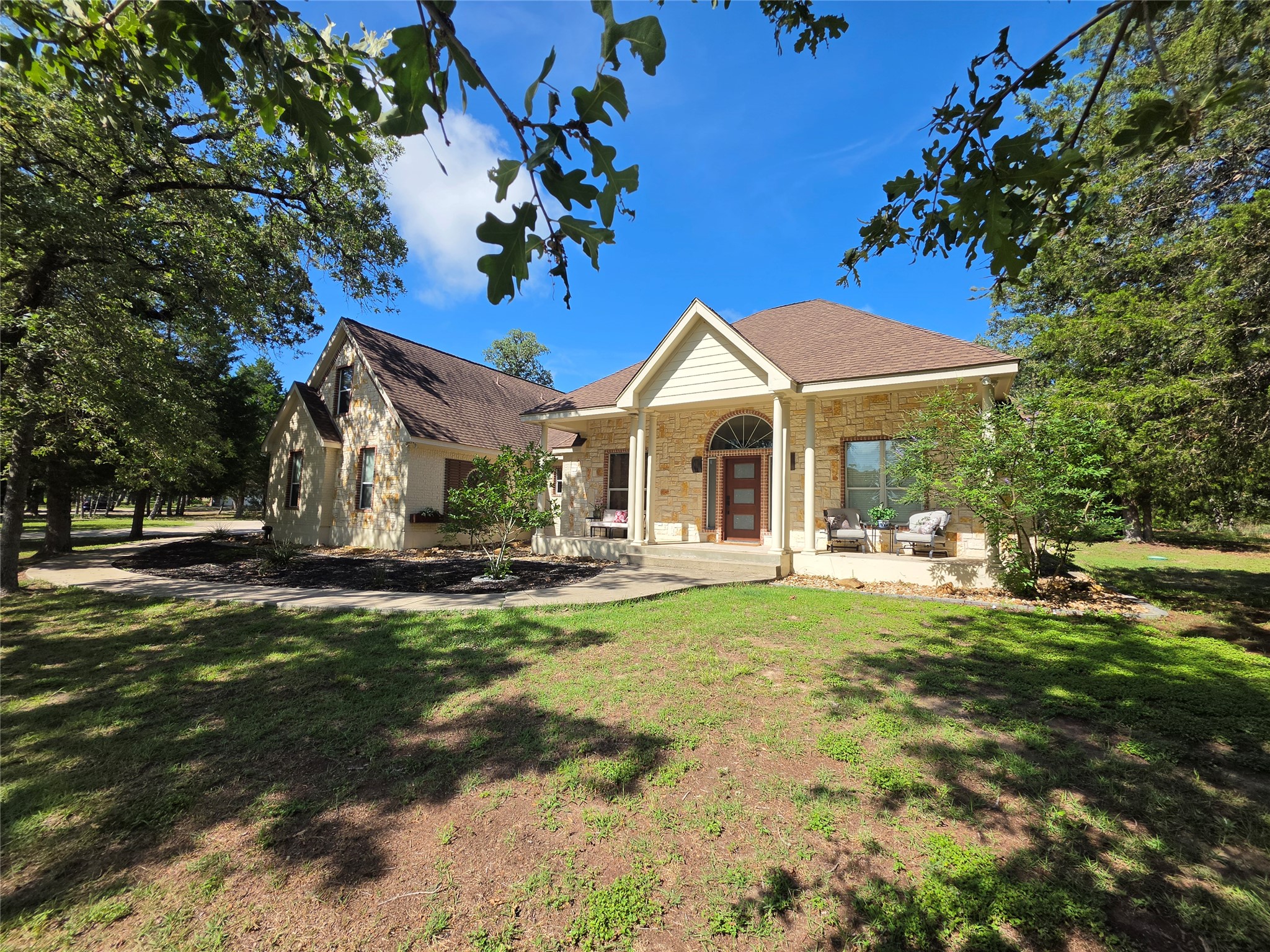 A welcoming front porch invites entry into this attractive stone-faced residence.