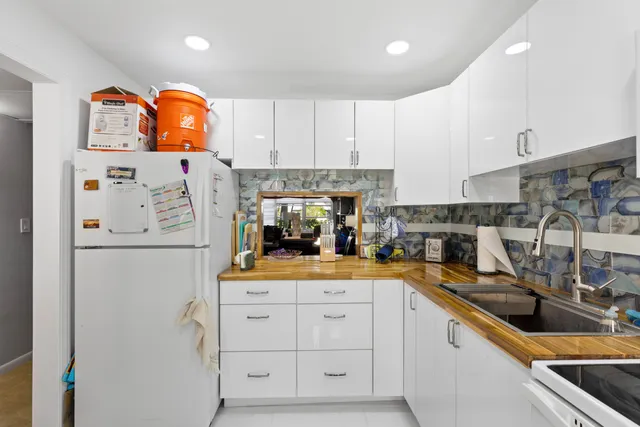 a kitchen with white cabinets and refrigerator