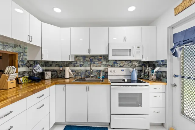 a kitchen with stainless steel appliances granite countertop a refrigerator sink stove and white cabinets