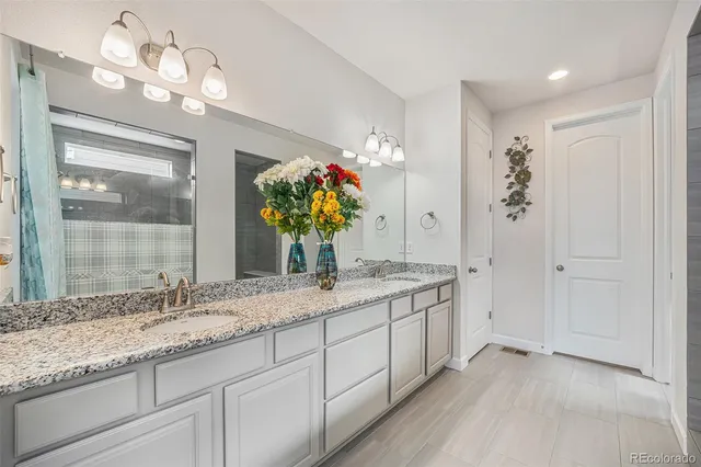 a bathroom with a granite countertop double vanity and a mirror