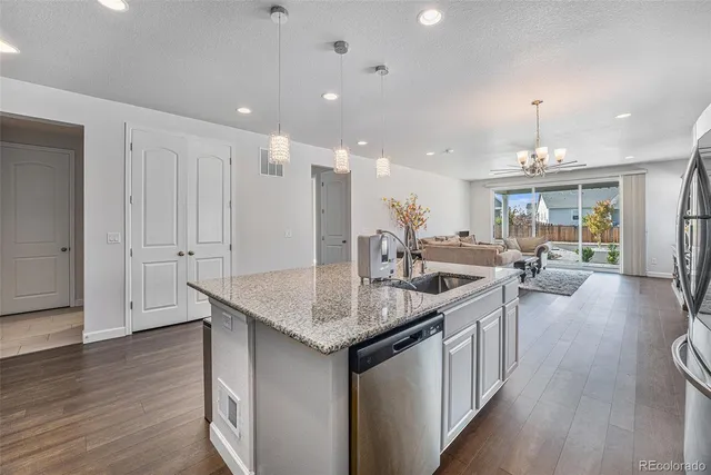 a kitchen with center island a sink dishwasher a stove and a dining table with wooden floor