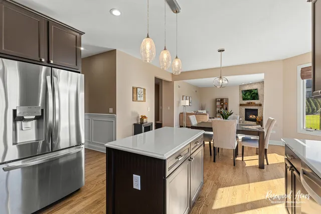 a kitchen with stainless steel appliances granite countertop a refrigerator a sink dishwasher a stove and white cabinets with wooden floor