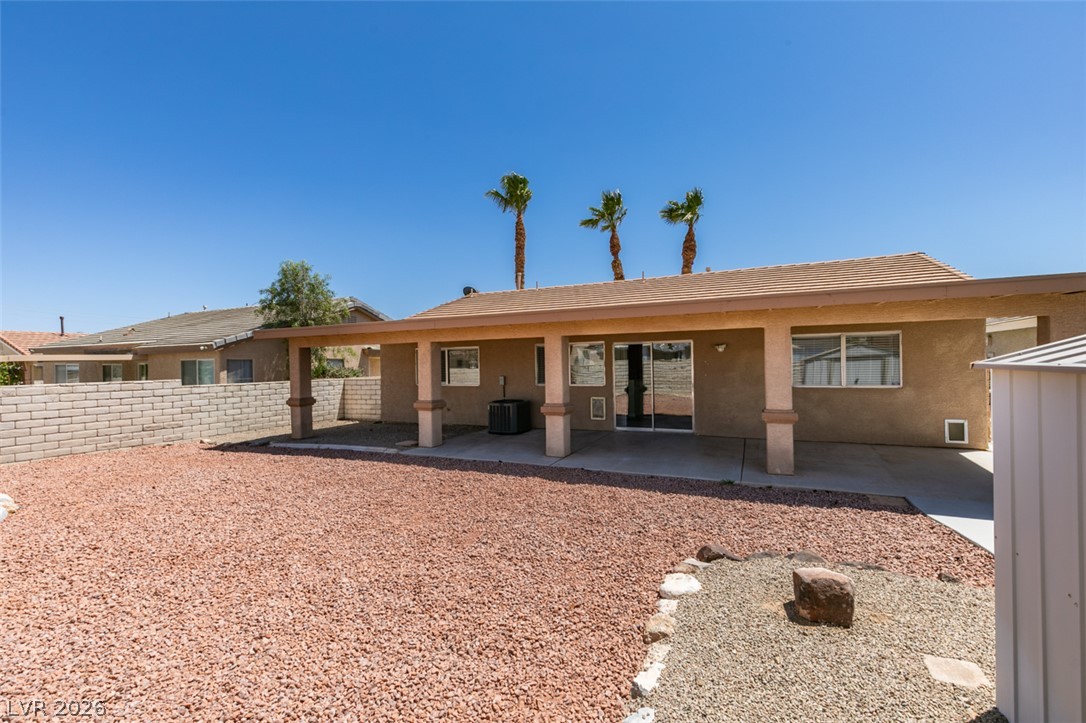 2028 Rustler Ridge Avenue North Las Vegas, NV 89031 - Photo 39 of 40 A spacious backyard with a large covered patio awaits, featuring palm trees and a low-maintenance landscape.