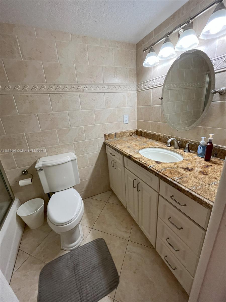 3090 North Course Drive, Unit 304 Pompano Beach, FL 33069 - Photo 12 of 16 a bathroom with a granite countertop toilet sink and mirror