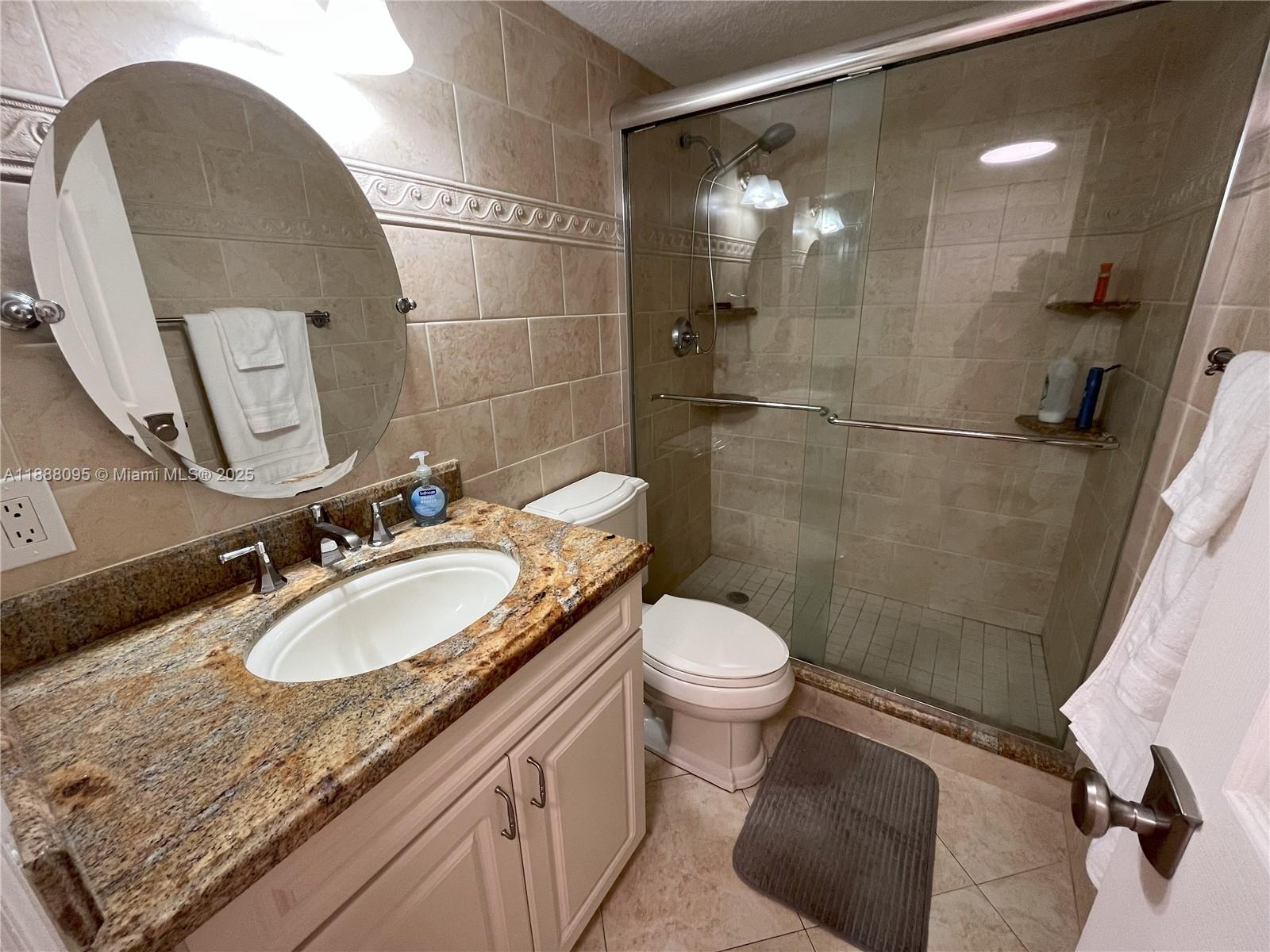 3090 North Course Drive, Unit 304 Pompano Beach, FL 33069 - Photo 15 of 16 a bathroom with a granite countertop sink a toilet and a shower