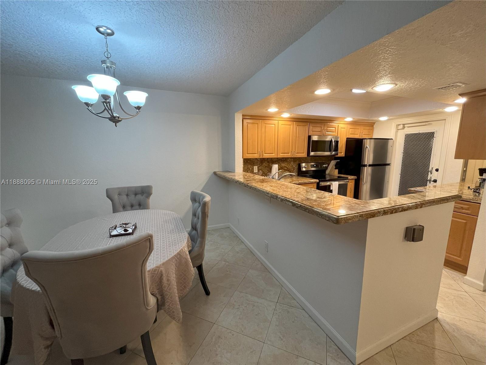 3090 North Course Drive, Unit 304 Pompano Beach, FL 33069 - Photo 2 of 16 a kitchen with a dining table a sink appliances and cabinets