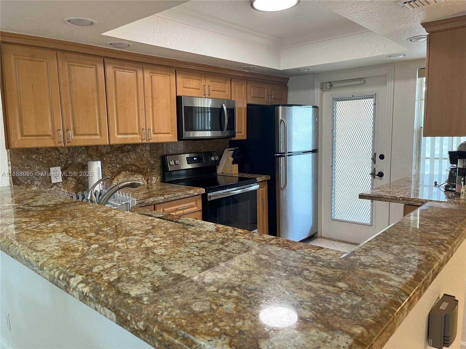 3090 North Course Drive, Unit 304 Pompano Beach, FL 33069 - Photo 3 of 16 a kitchen with stainless steel appliances granite countertop a refrigerator a stove a sink and a microwave