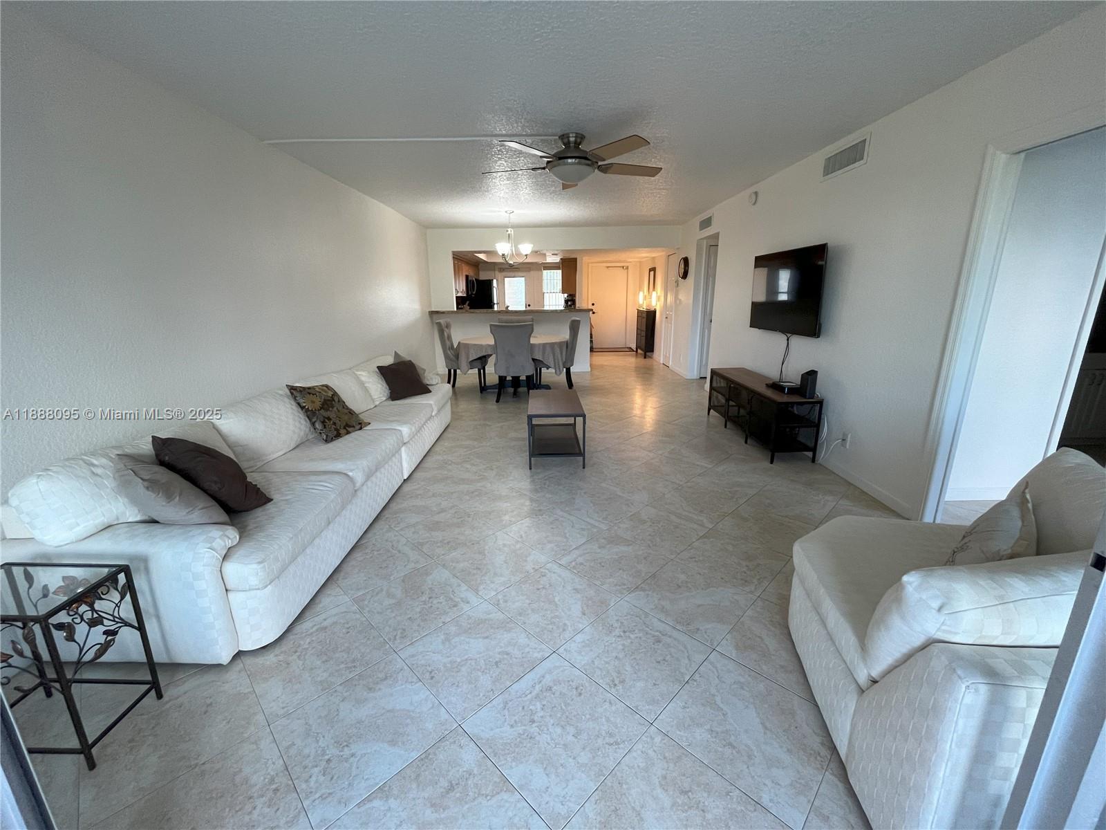 3090 North Course Drive, Unit 304 Pompano Beach, FL 33069 - Photo 8 of 16 a living room with furniture and a chandelier