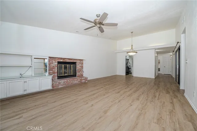 a view of an empty room with window and chandelier fan