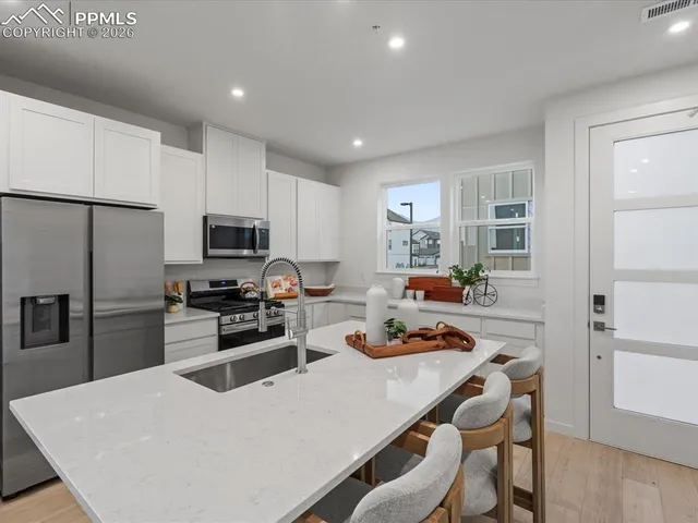 a kitchen with stainless steel appliances granite countertop a stove refrigerator a sink dishwasher with a dining table and chairs