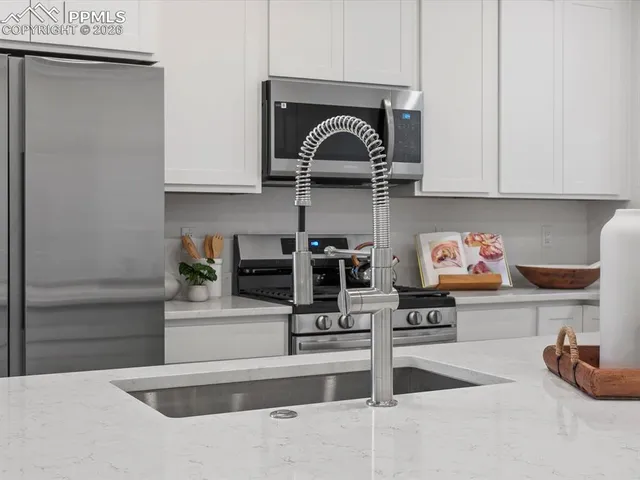 a kitchen with stainless steel appliances granite countertop a sink and white cabinets