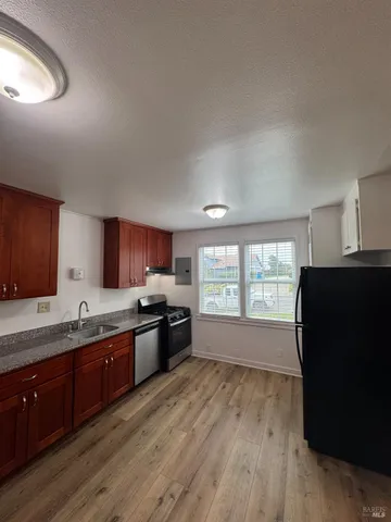 a kitchen with stainless steel appliances granite countertop a sink a stove a refrigerator a sink and dishwasher with wooden floor