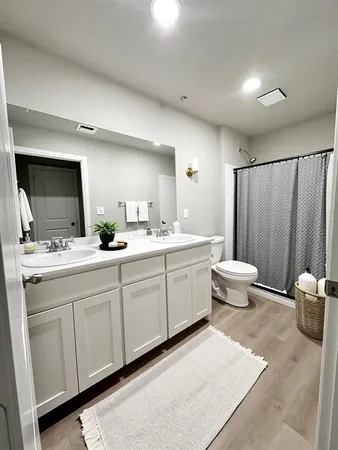 a spacious bathroom with a double vanity sink a mirror and a toilet