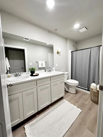 a spacious bathroom with a double vanity sink a mirror and a toilet