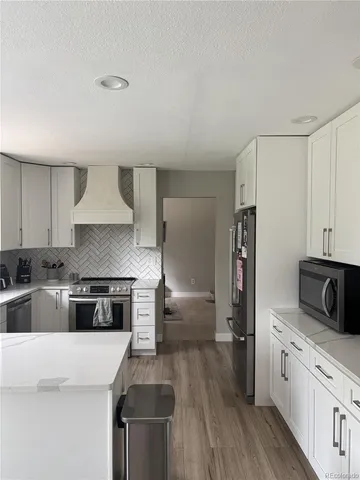a kitchen with granite countertop a refrigerator stove top oven and sink