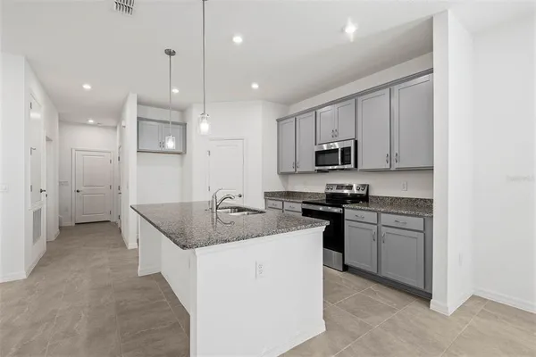 a kitchen with stainless steel appliances granite countertop a sink and stove top oven with wooden floor