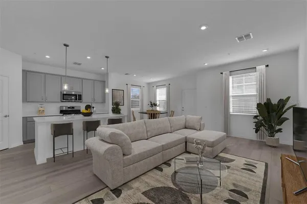 a living room with furniture white cabinets and a dining table with kitchen view