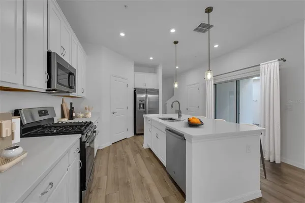 a kitchen with stainless steel appliances a stove a sink a refrigerator and cabinets