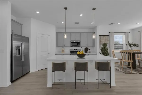 a kitchen view with stainless steel appliances kitchen island granite countertop a table chairs and a refrigerator