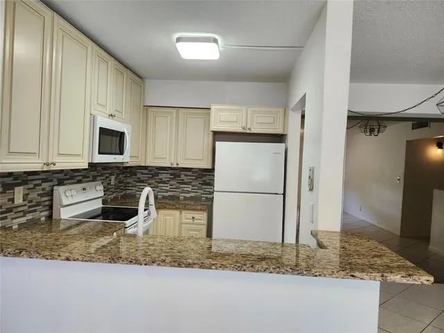 a kitchen with stainless steel appliances granite countertop a sink a refrigerator and a granite counter tops