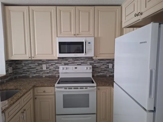 a kitchen with white cabinets and a stove with a refrigerator