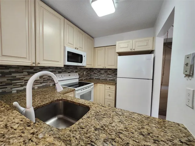 a kitchen with a refrigerator sink and cabinets