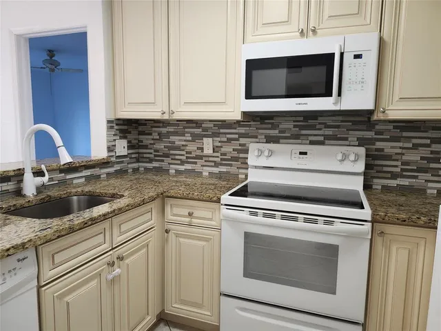 a kitchen with granite countertop white cabinets stainless steel appliances and sink