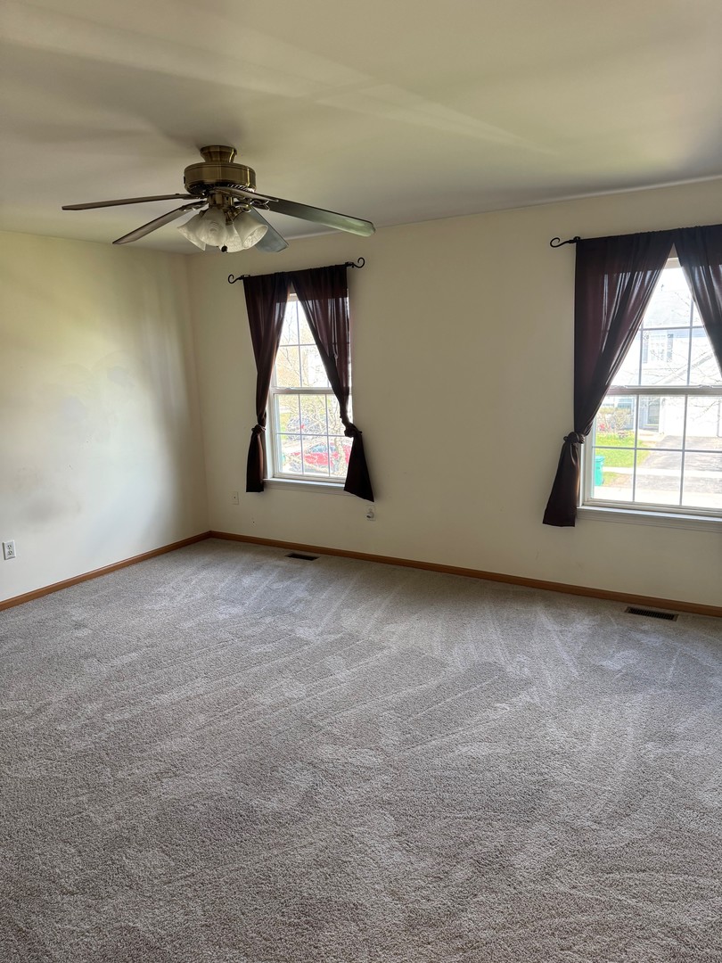 674 Shannon Drive, Unit 674 Romeoville, IL 60446 - Photo 12 of 13 an empty room with windows and fan