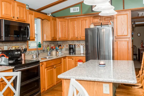 a kitchen with stainless steel appliances granite countertop a refrigerator a stove and a sink with wooden floor