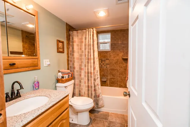 a bathroom with a granite countertop sink toilet mirror and bathtub