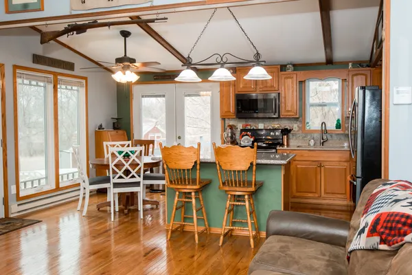 a dining room with wooden floor a chandelier a glass table and chairs