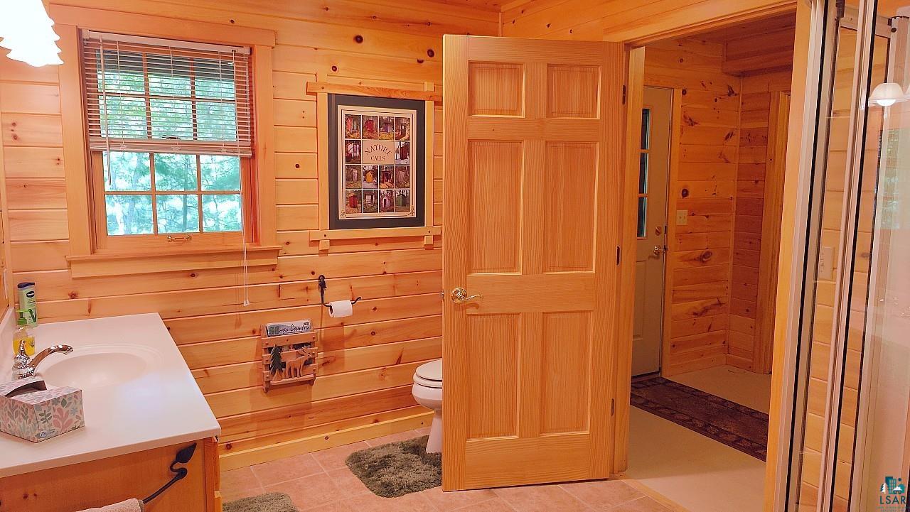 2357 Retreat Lodge Road Cook, MN 55723 - Photo 26 of 60 Full bath with vanity, wood walls, tile patterned flooring, and a shower