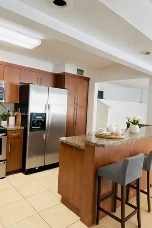 a kitchen with granite countertop a refrigerator and a stove top oven