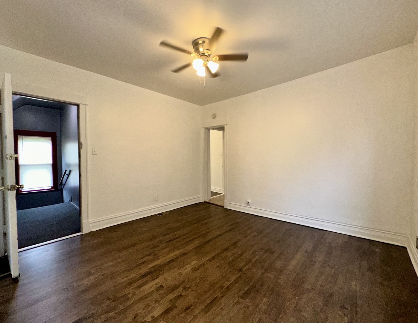10749 South State Street Chicago, IL 60628 - Photo 19 of 31 an empty room with wooden floor chandelier fan and windows