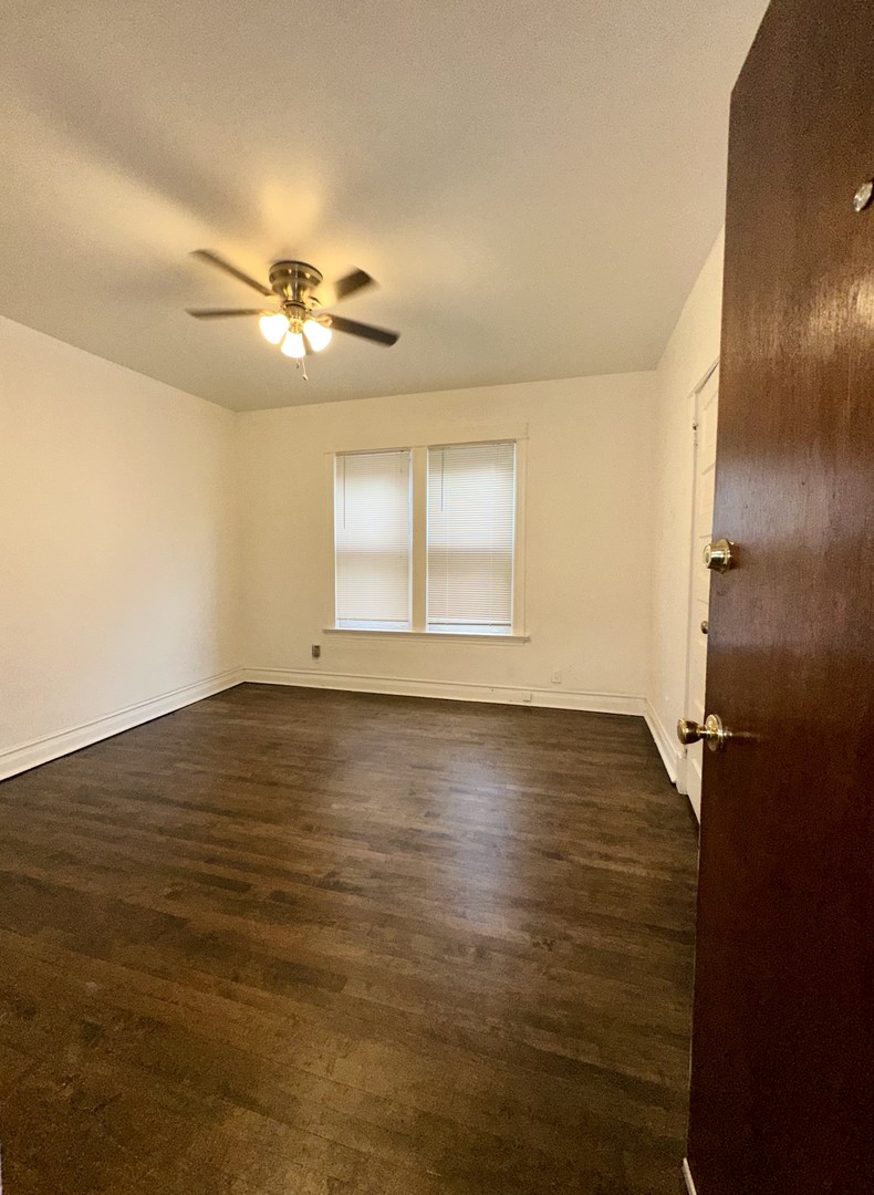 10749 South State Street Chicago, IL 60628 - Photo 20 of 31 a view of an empty room with window and wooden floor