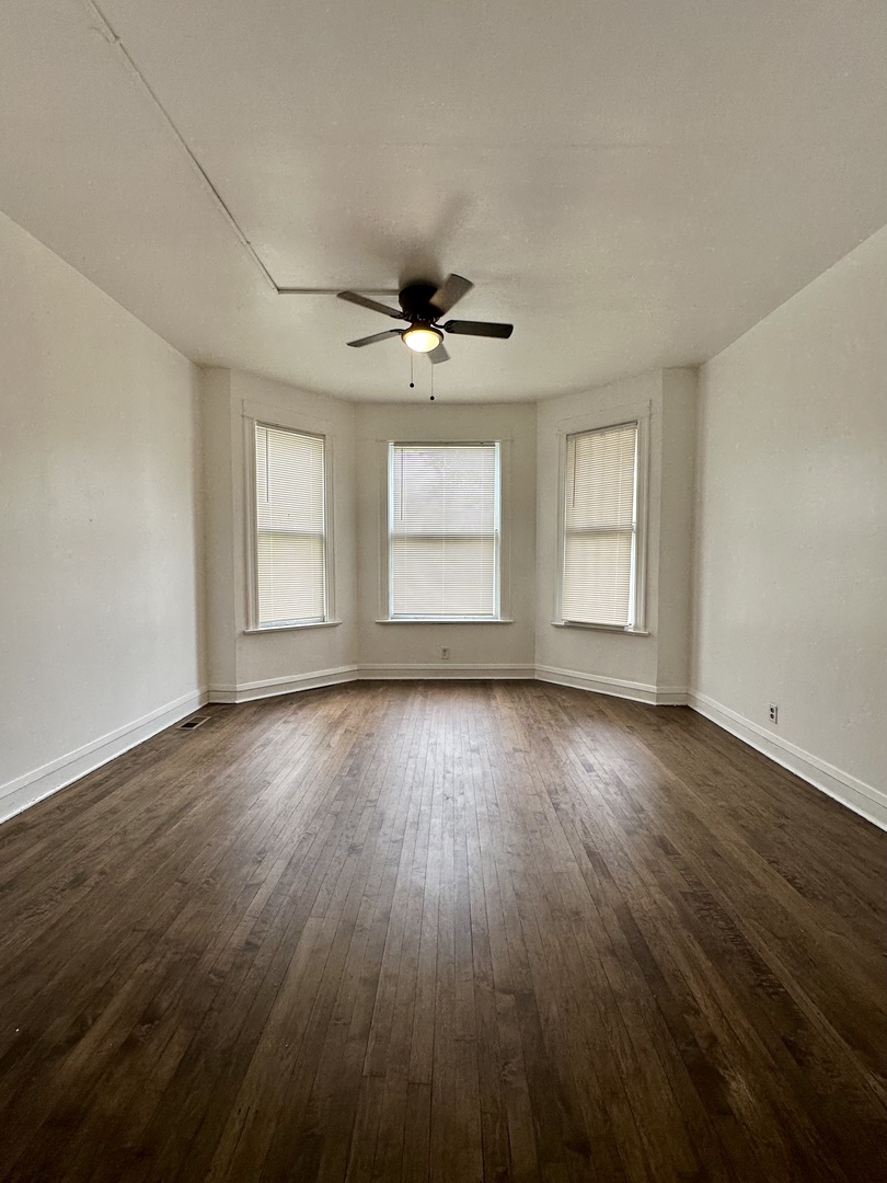 10749 South State Street Chicago, IL 60628 - Photo 6 of 31 an empty room with wooden floor and windows