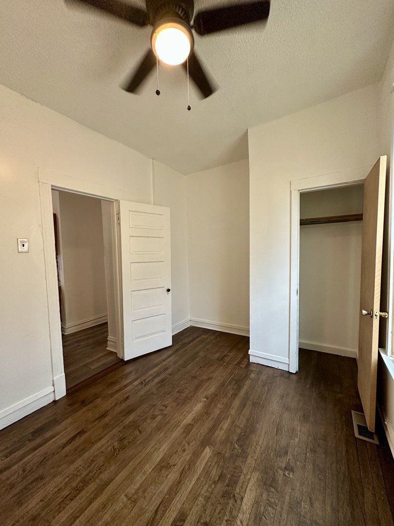 10749 South State Street Chicago, IL 60628 - Photo 10 of 31 an empty room with wooden floor closet and windows
