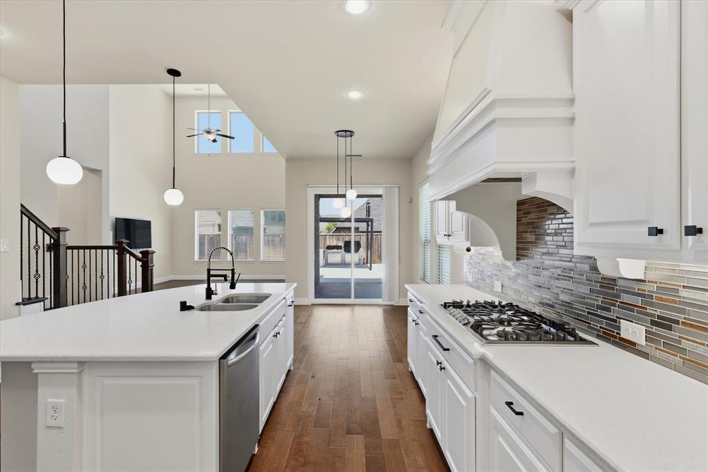 2433 Mare Road Carrollton, TX 75010 - Photo 5 of 37 Gourmet kitchen with white cabinetry, gas cooktop, stone countertops, and tile backsplash