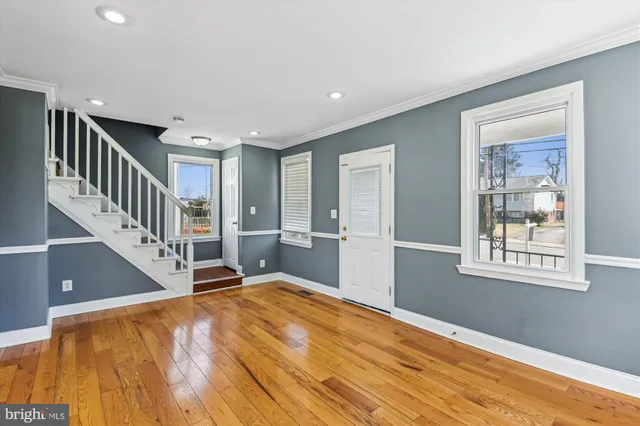 a view of an entryway with wooden floor leading to a furnished livingroom and windows