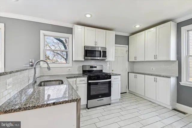 a kitchen with granite countertop a stove sink and microwave