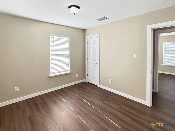 an empty room with wooden floor and windows
