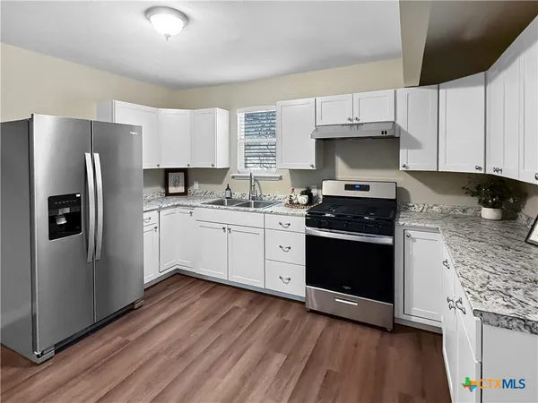 a kitchen with a sink a refrigerator and cabinets