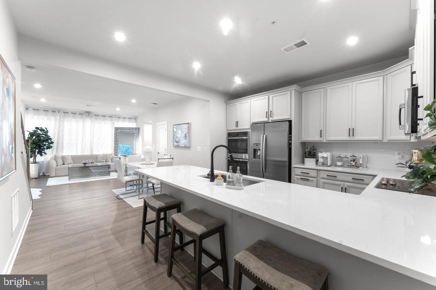 43785 Transit Square Ashburn, VA 20147 - Photo 4 of 40 a kitchen with stainless steel appliances kitchen island granite countertop a stove a sink a refrigerator and white cabinets with wooden floor