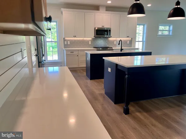 a kitchen with stainless steel appliances a sink a stove a refrigerator cabinets and a dining table