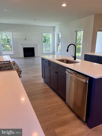 a living room with stainless steel appliances a kitchen island hardwood floor sink stove and a window