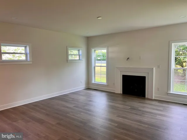 an empty room with wooden floor fireplace and windows