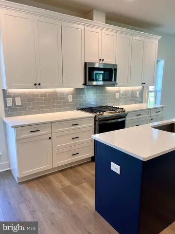a kitchen with stainless steel appliances granite countertop a sink dishwasher a stove and a microwave oven with cabinets
